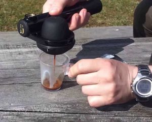 un café en train d'être servi sur une table de camping avec la machine à expresso portable Handpresso Pump