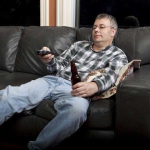 homme avec télécommande et bière à la main dans un canapé