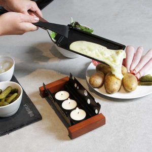 appareil à raclette à bougie Partyclette versant fromage fondu sur des pommes de terre